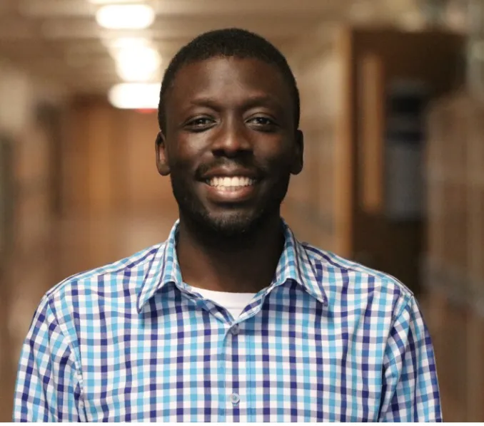 Amos, OpenStax educator, smiling in a hallway